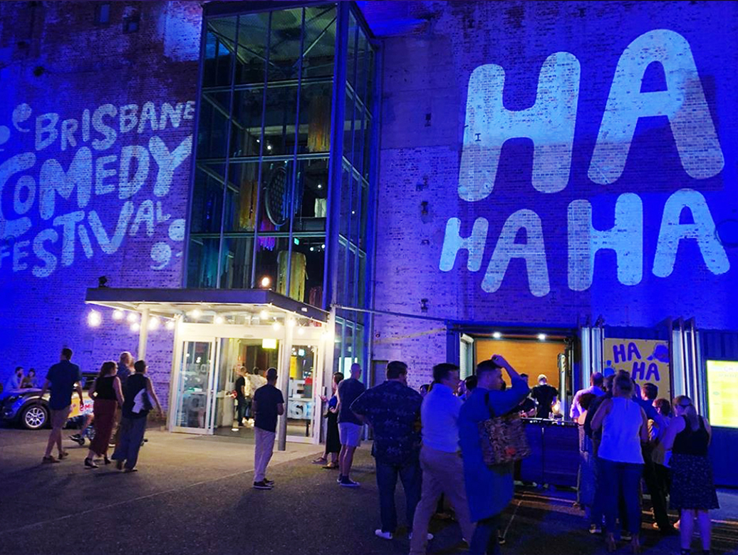 Brisbane Comedy Festival and HaHa projected onto Brisbane Powerhouse building façade