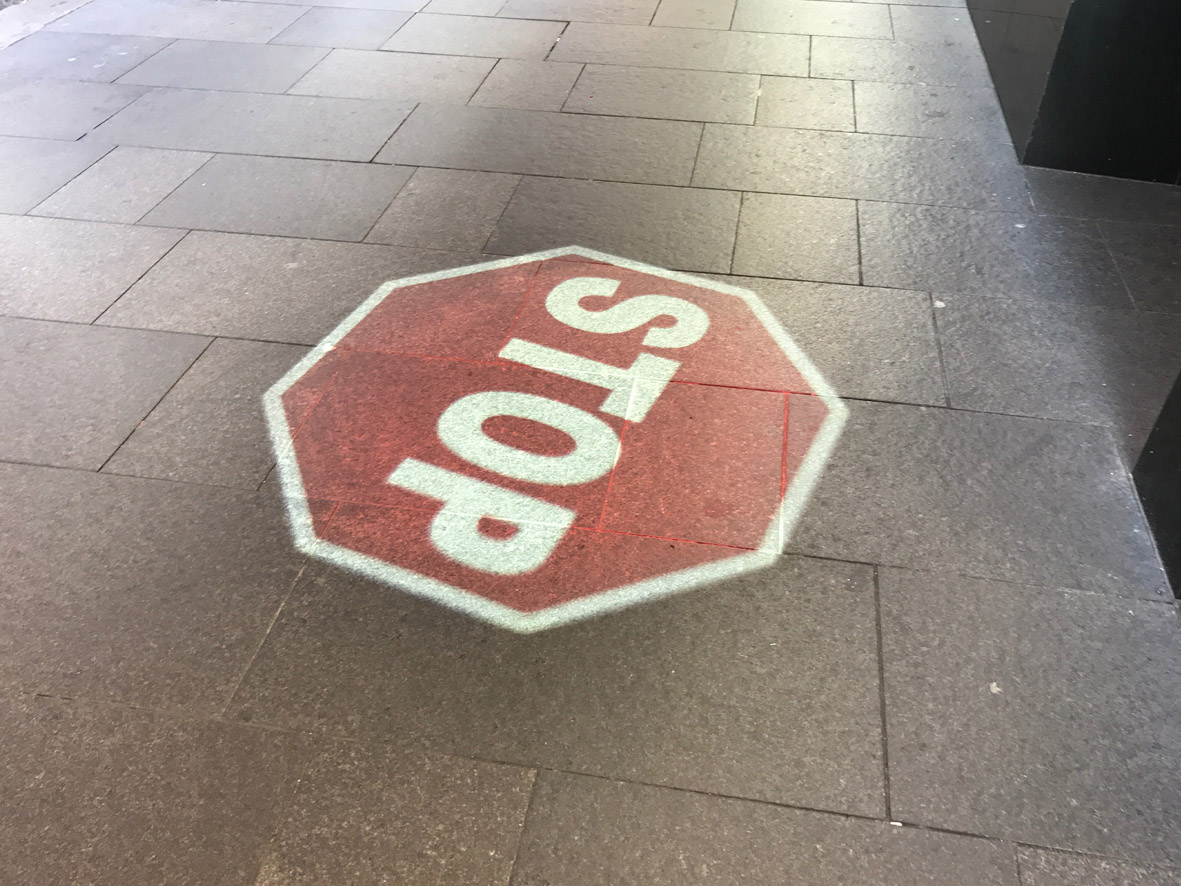 STOP sign projected onto footpath during the day