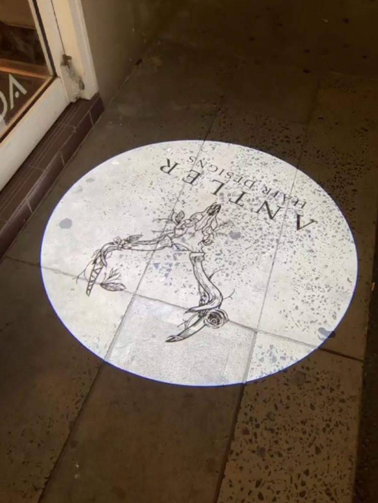 Antler Hair Design gobo projection onto footpath outside the store entrance